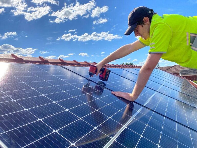 Technician installing rooftop solar panels using drill