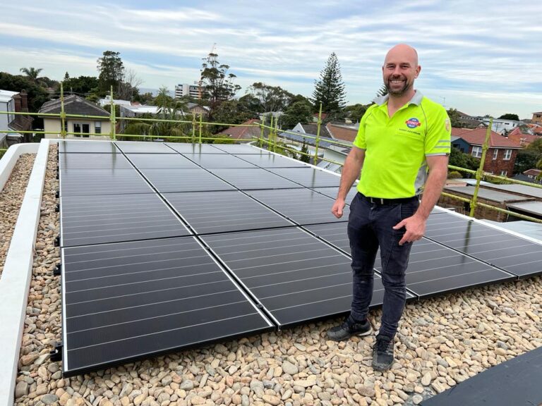Rooftop solar panels with smiling technician nearby