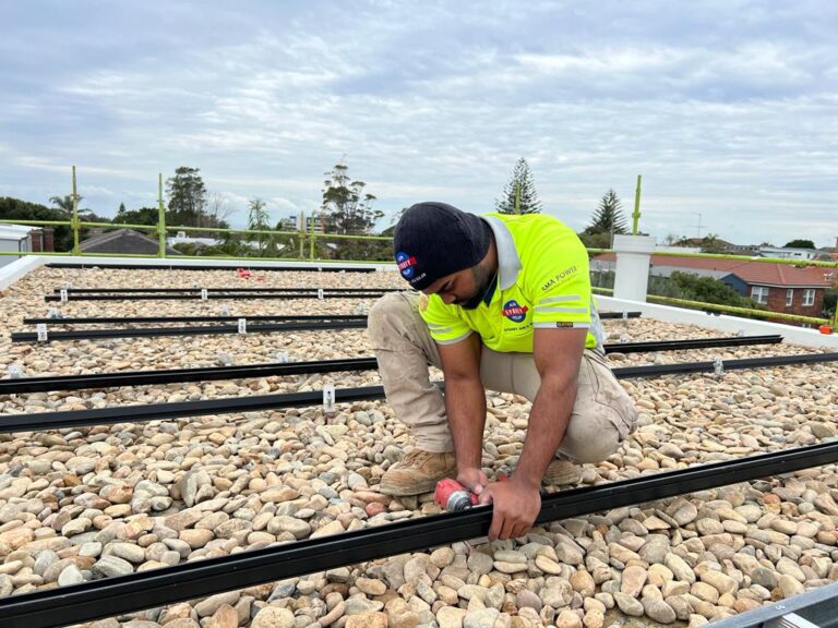 Roofer installing solar panel mounting rails on rooftop