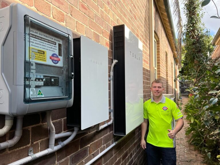 Tesla Powerwall battery mounted on brick wall