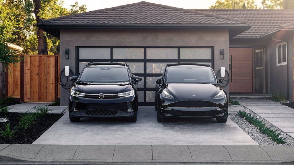 Two black electric cars charging at driveway