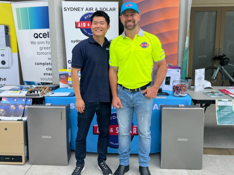 Two men beside Q CELLS solar battery units