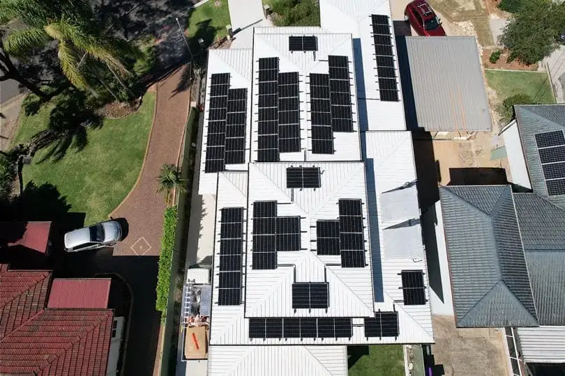 Aerial view of a home with black solar panels across the roof