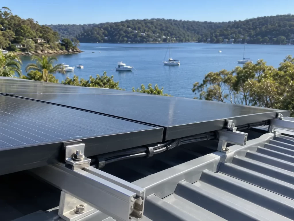 Solar panels with stainless steel mounting rails on a metal roof near the water in southern Sydney